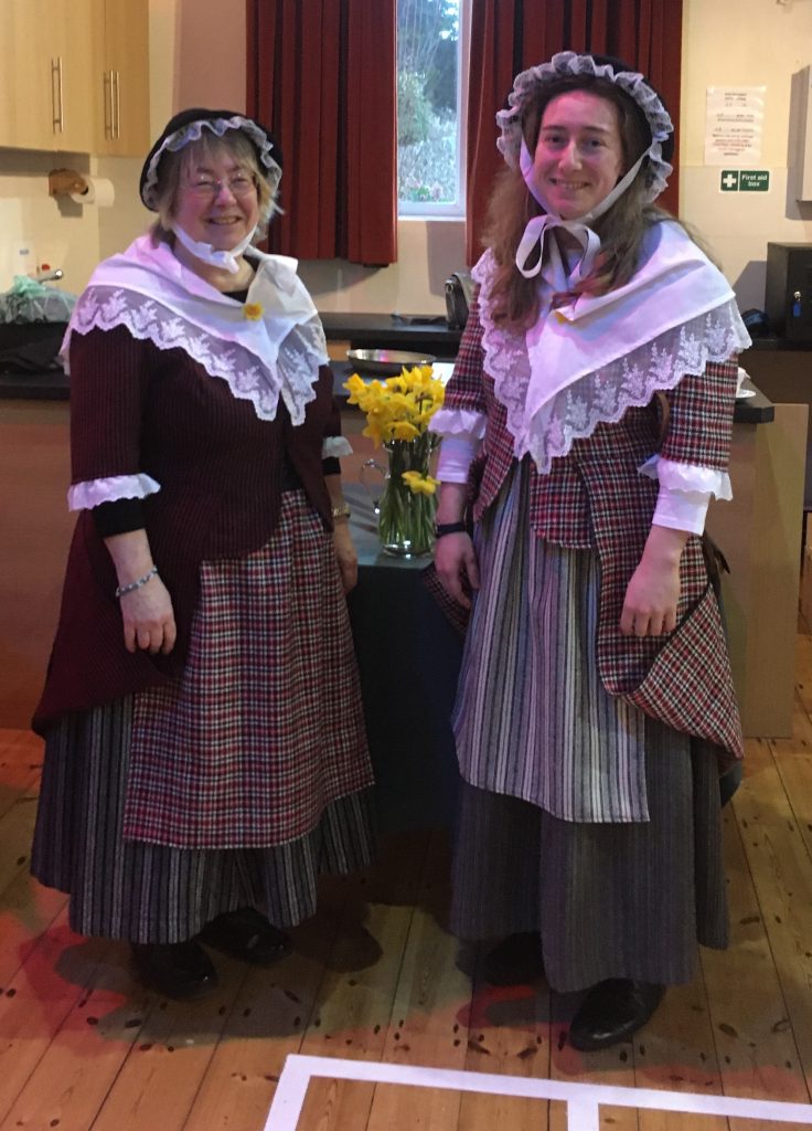 Two local women in traditional Welsh wool costumes, with the betgwns, skirts, pinnies, shawls and hats.