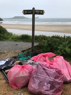 Bags of plastic waste and other litter collected from beach, ready for recycling.