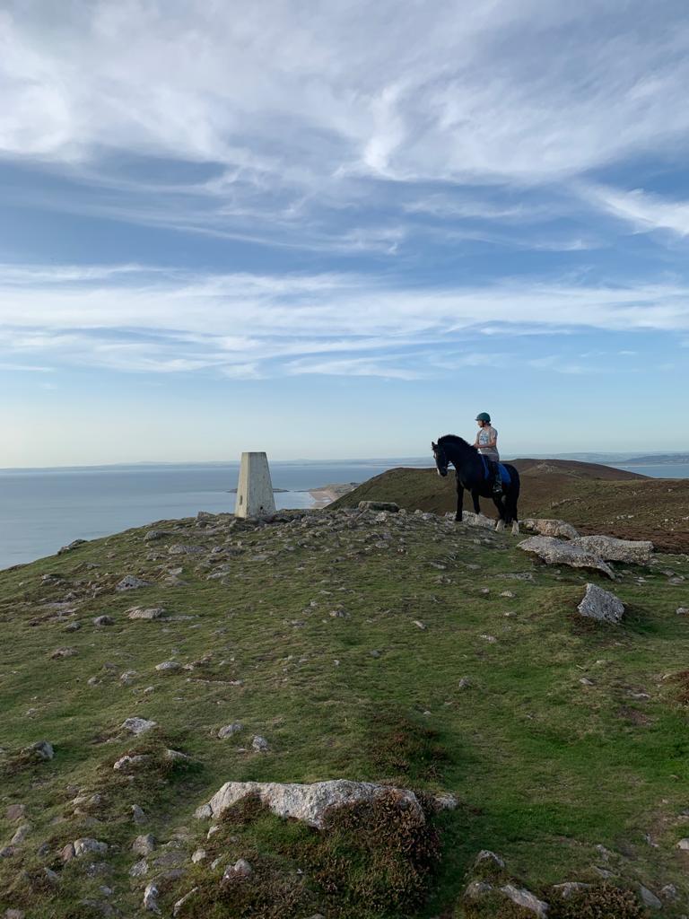 Horse and rider next to the Trig Point pillar.