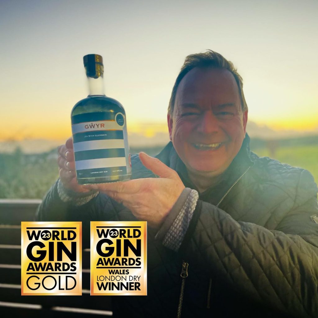 Gower Gin director with bottle of gin and World Gin Gold awards